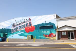 A mural on the side of a building with a sign that reads maraschino cherries.